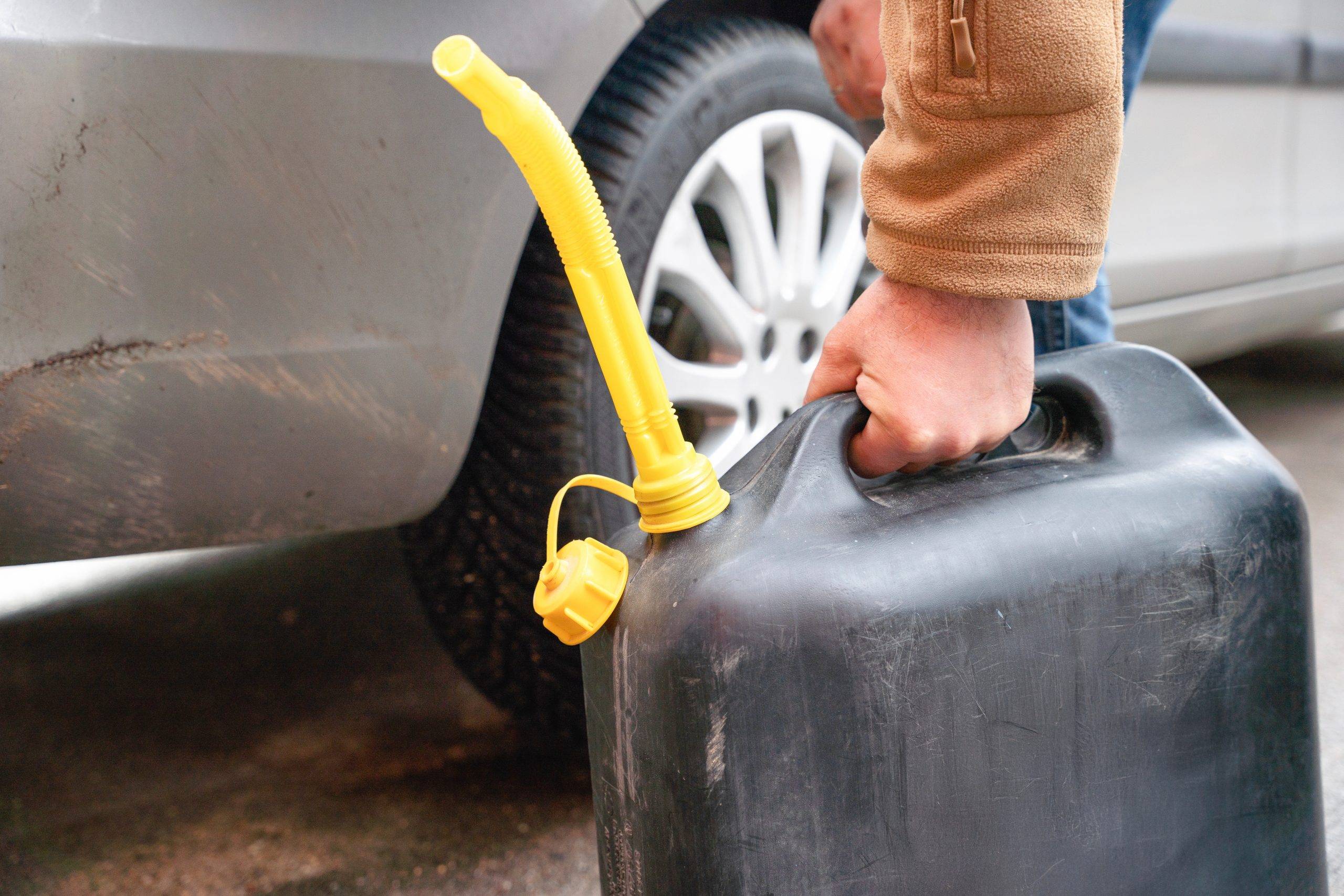 Person Filling Vehicle With Fuel From Portable Canister On Roadside