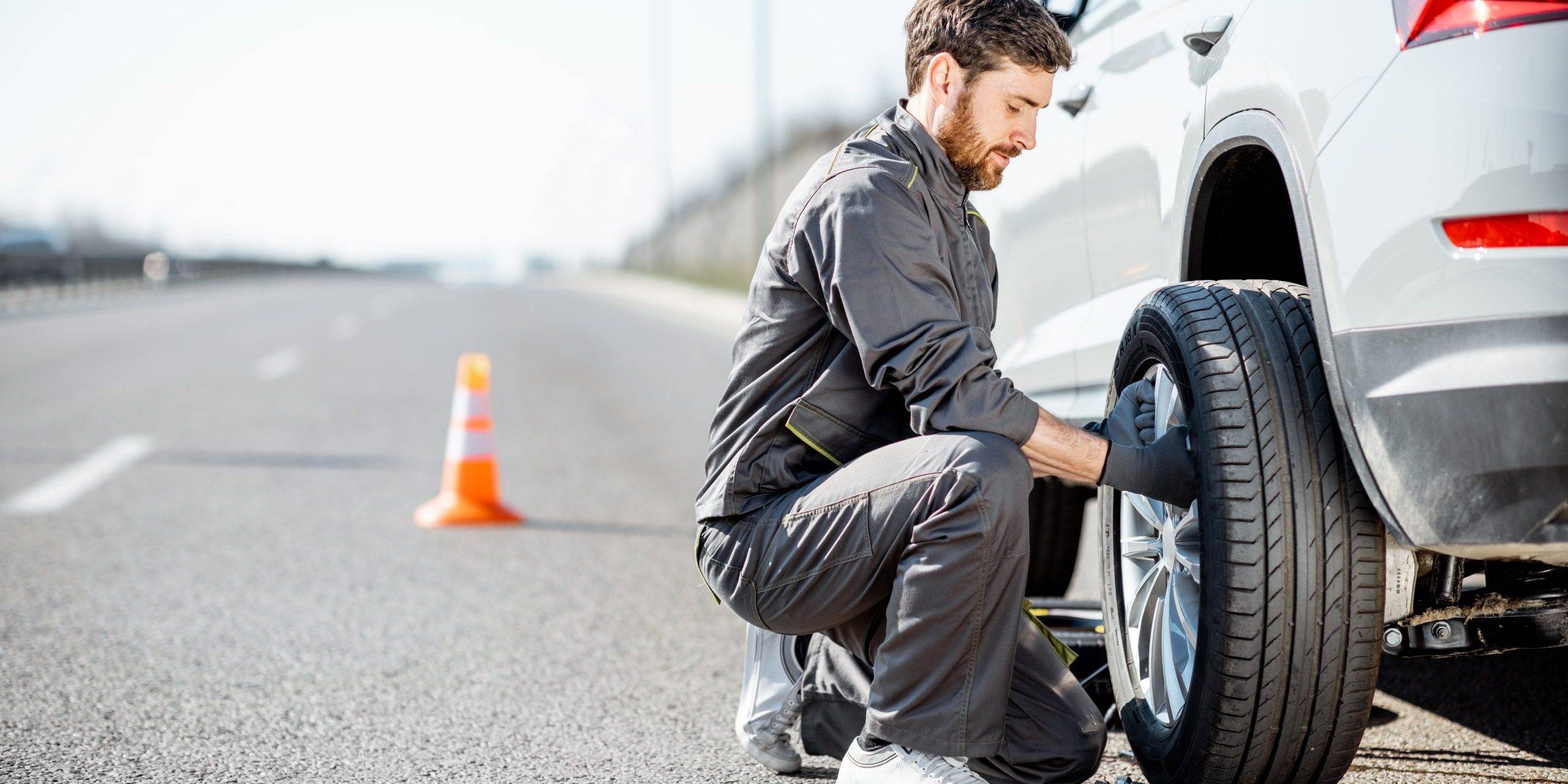 Worker Changing Car Wheel On The Highway Worker Changing Car Wheel On The Highway